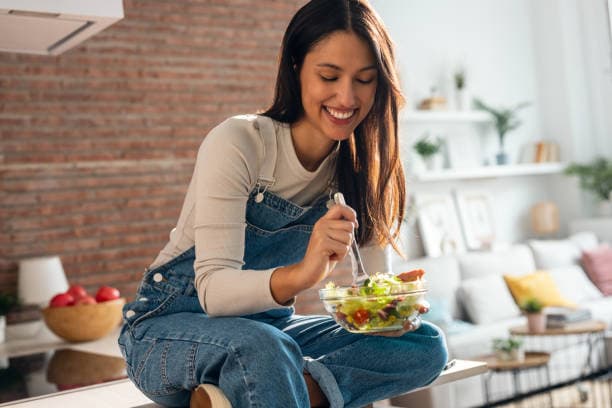 Woman smiling eating a healthy meal at home